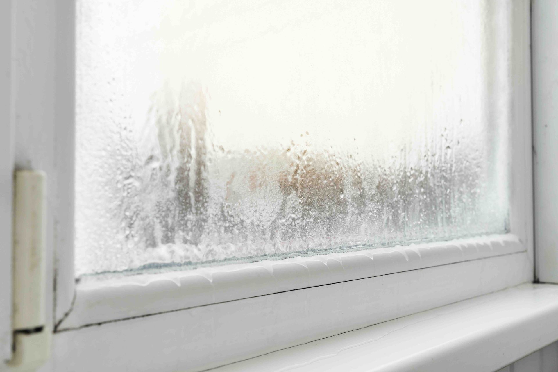 Close-up of a white window with condensation; the glass is blurred.