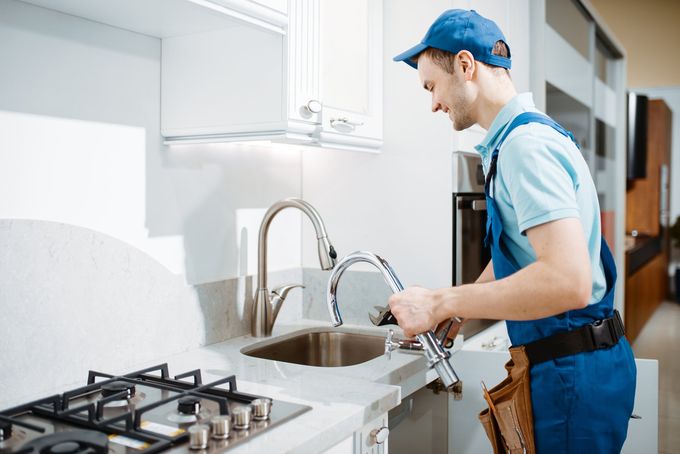 plumber fixing kitchen faucet