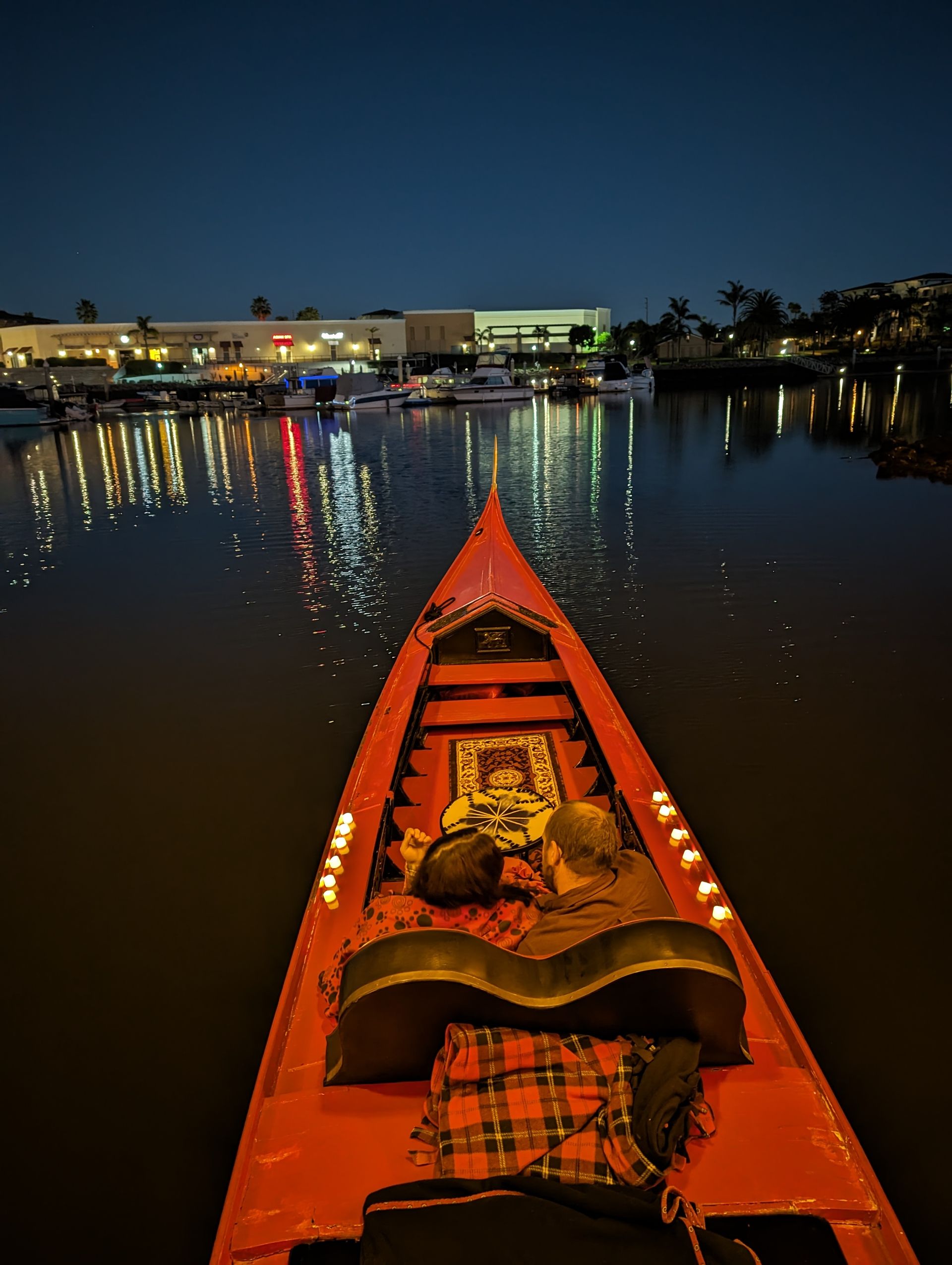 A red boat is floating on a body of water at night