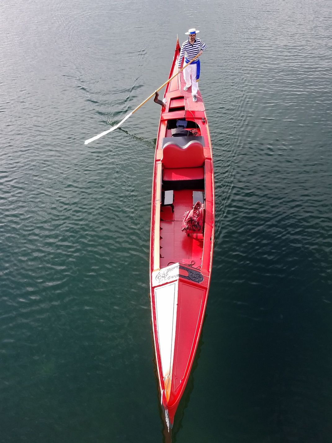 A man is rowing a red boat in the water