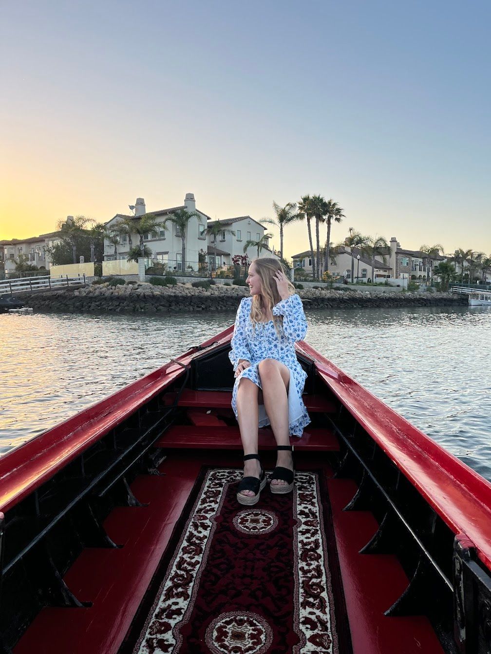 A woman is sitting in the back of a boat on the water.