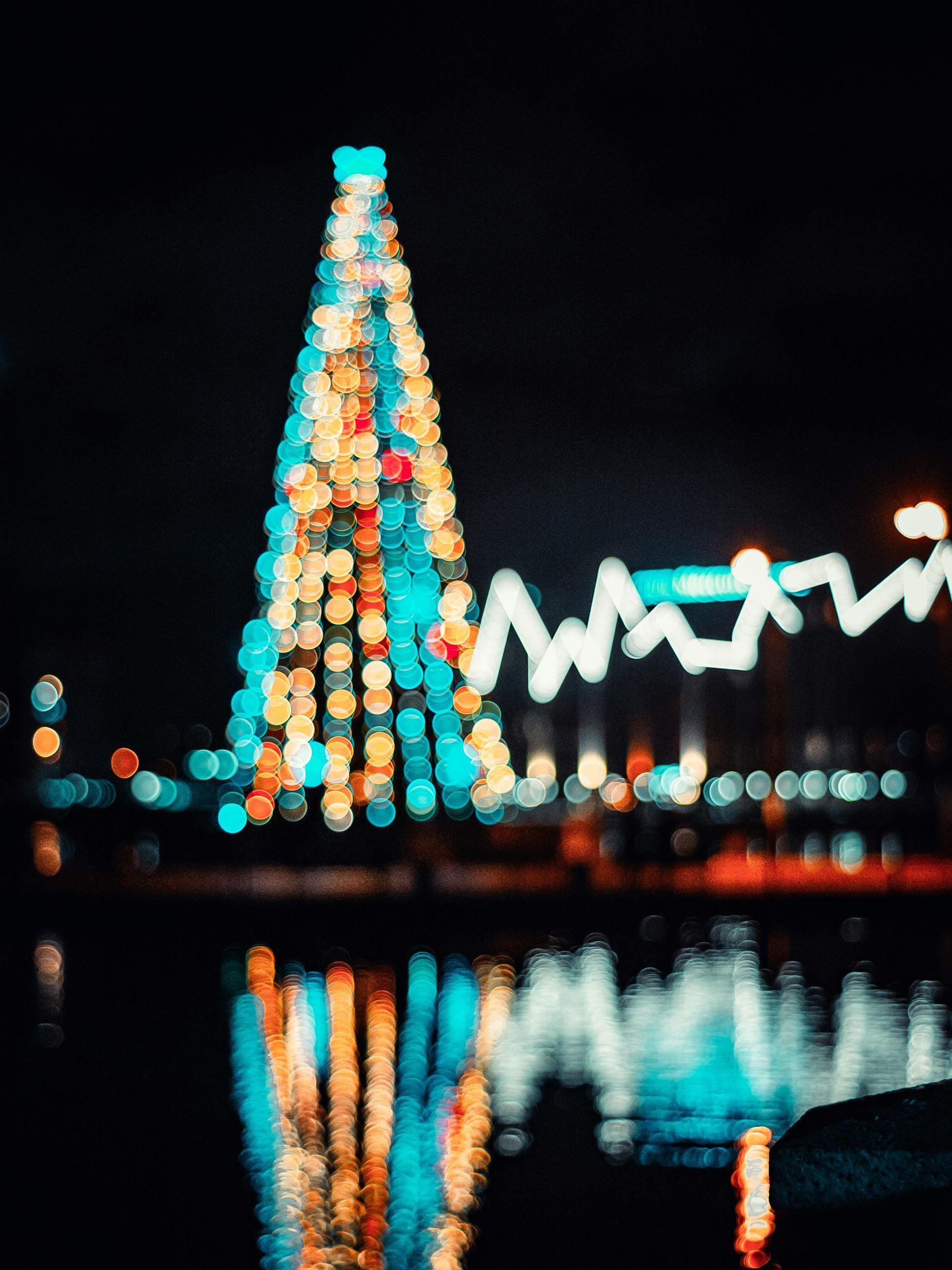 A blurry picture of a christmas tree in the water at night