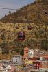 A cable car is going up a hill over a city.
