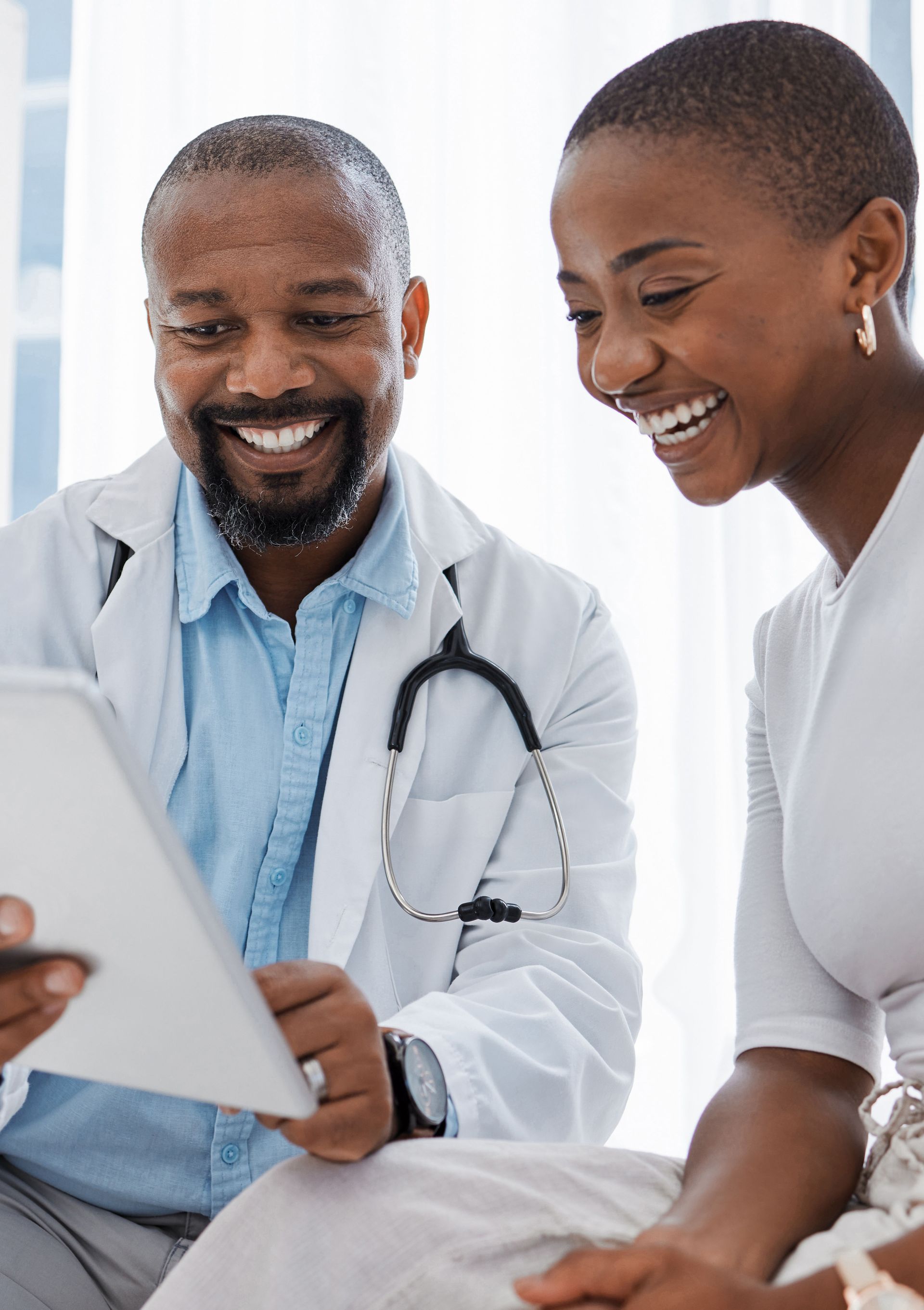 A doctor and a patient are looking at a tablet together.