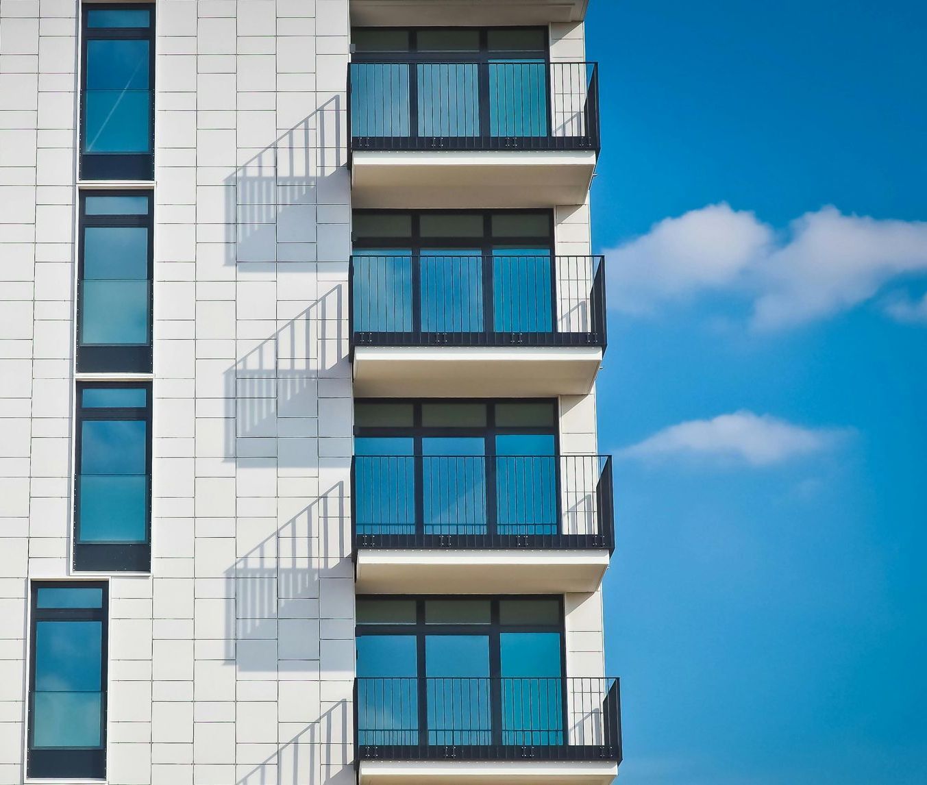 A tall building with a lot of windows and balconies against a blue sky.