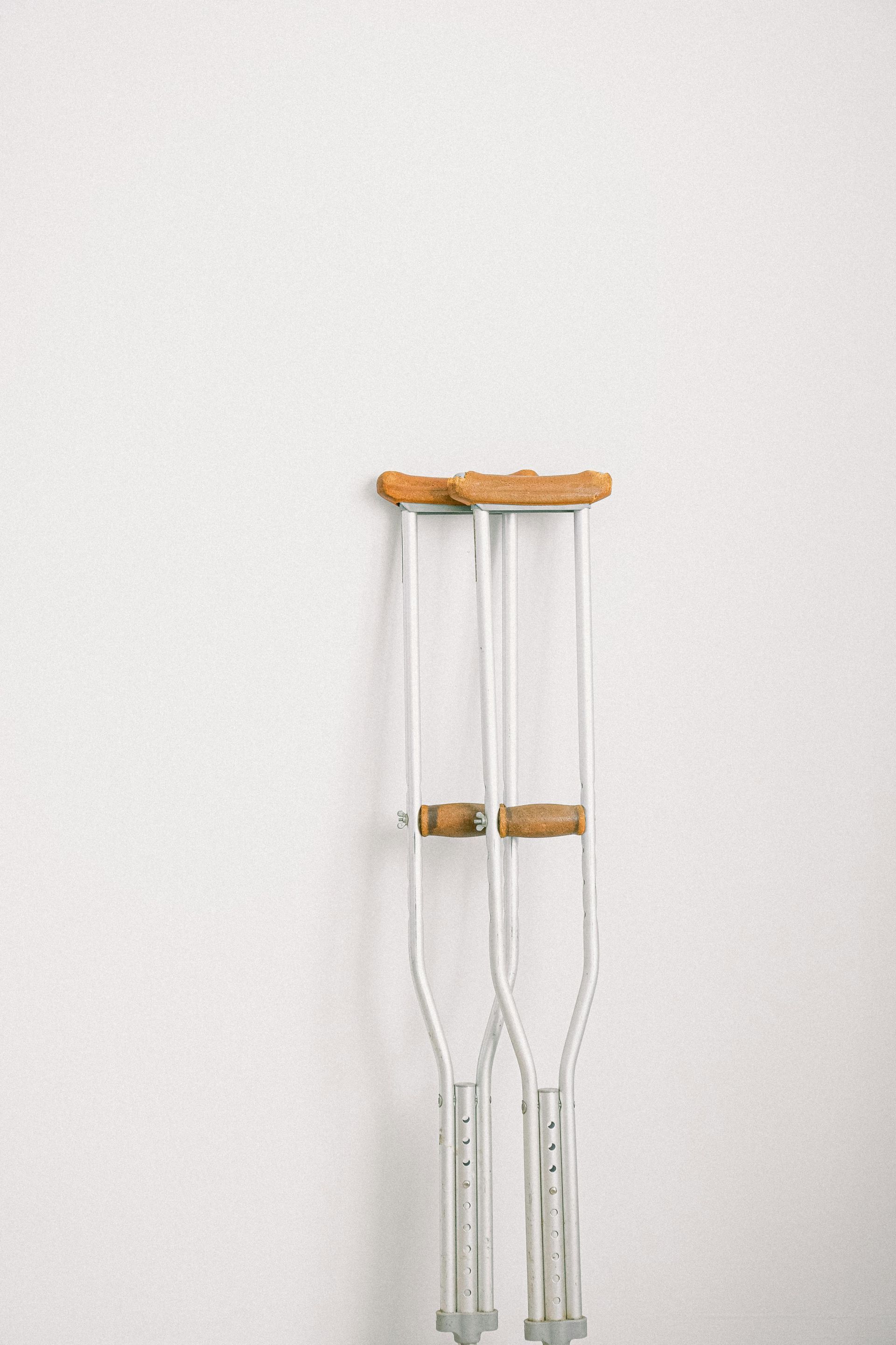 A pair of crutches hanging on a white wall.