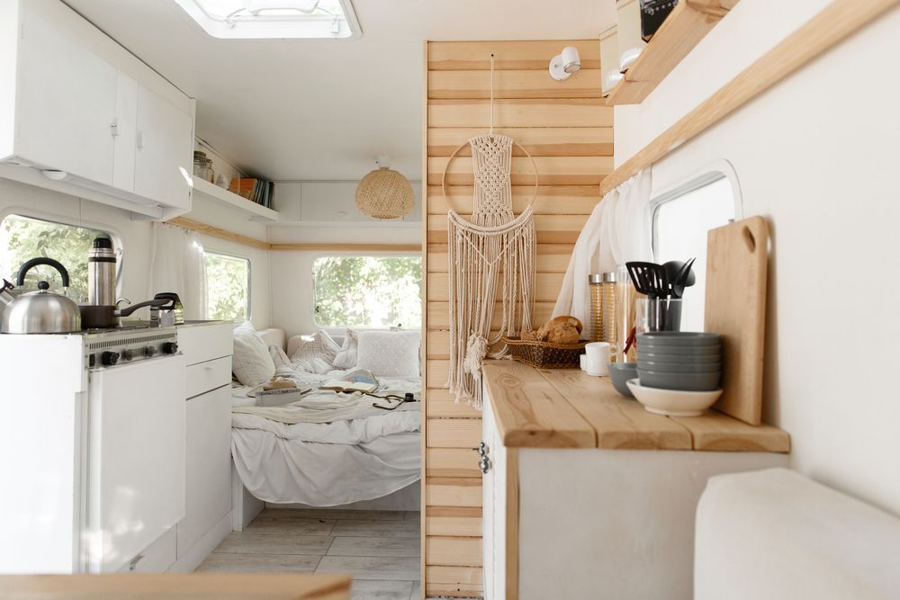 A kitchen in a camper with a bed and a stove.