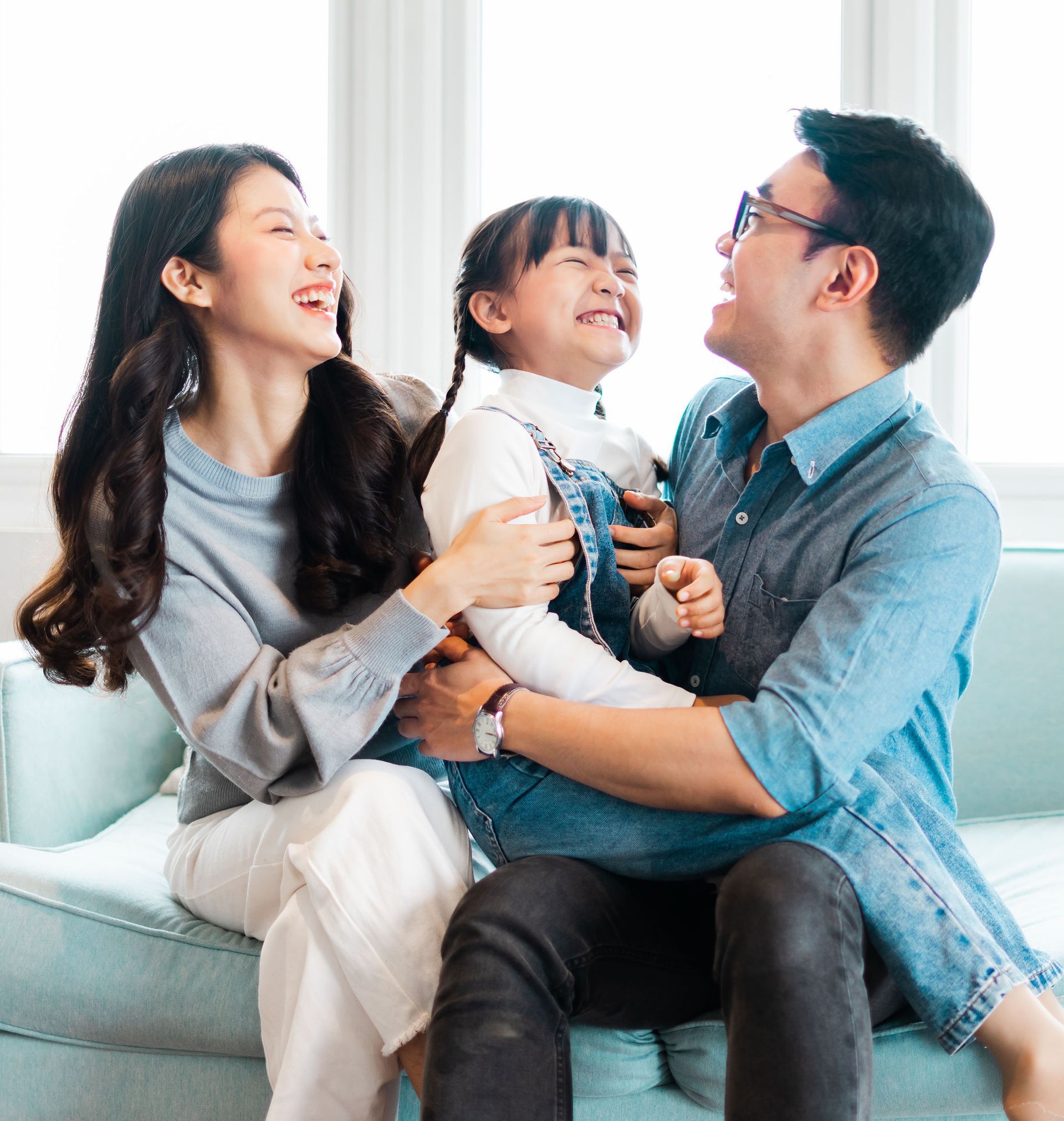 A man and woman are sitting on a couch with a little girl.