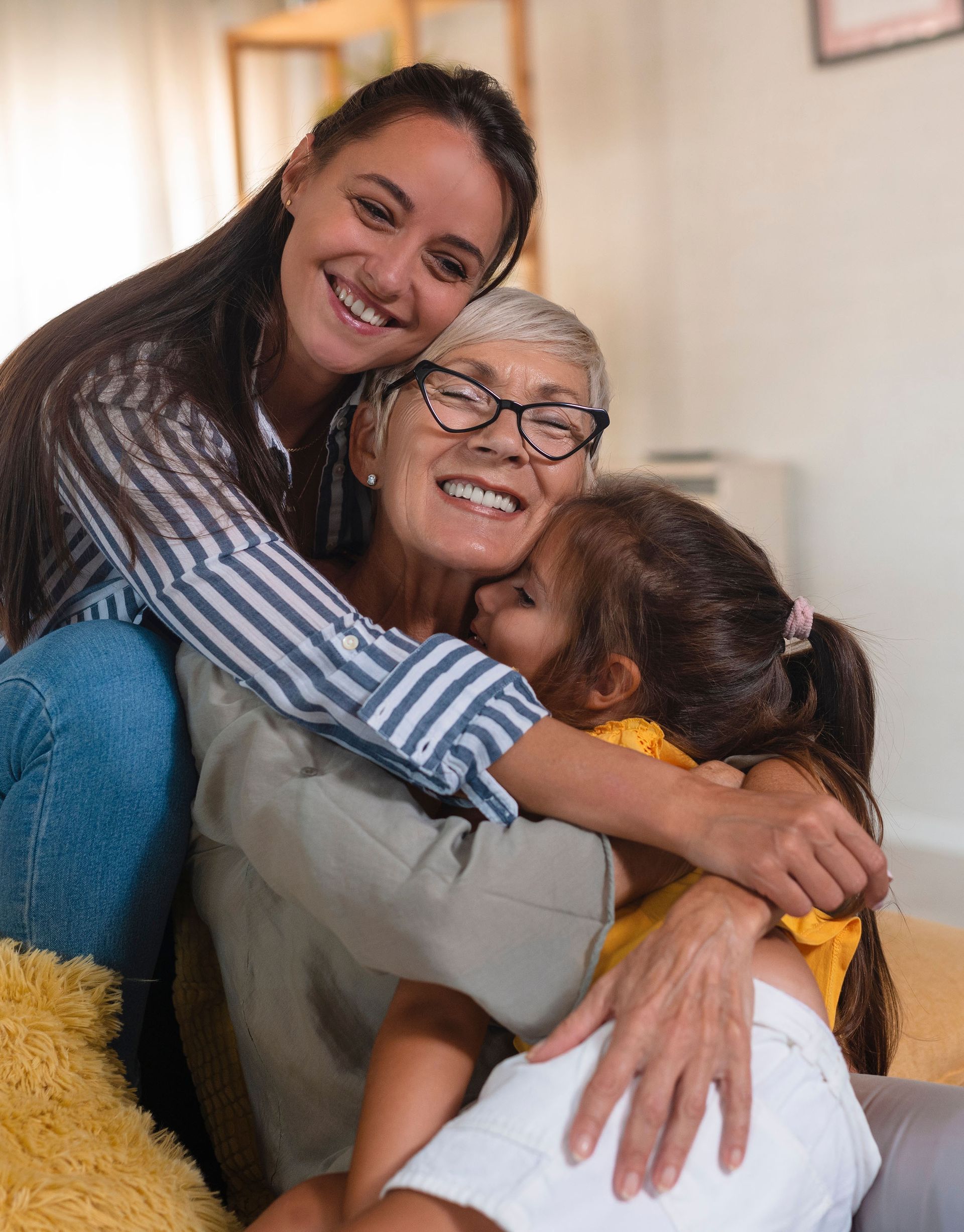 A woman and two children are hugging each other on a couch.