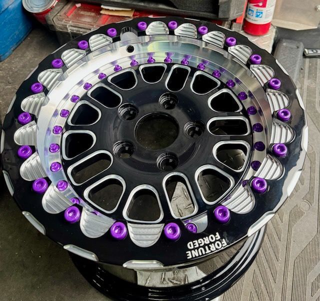 Black and silver alloy car wheel with purple accents and Fortune Forged branding.