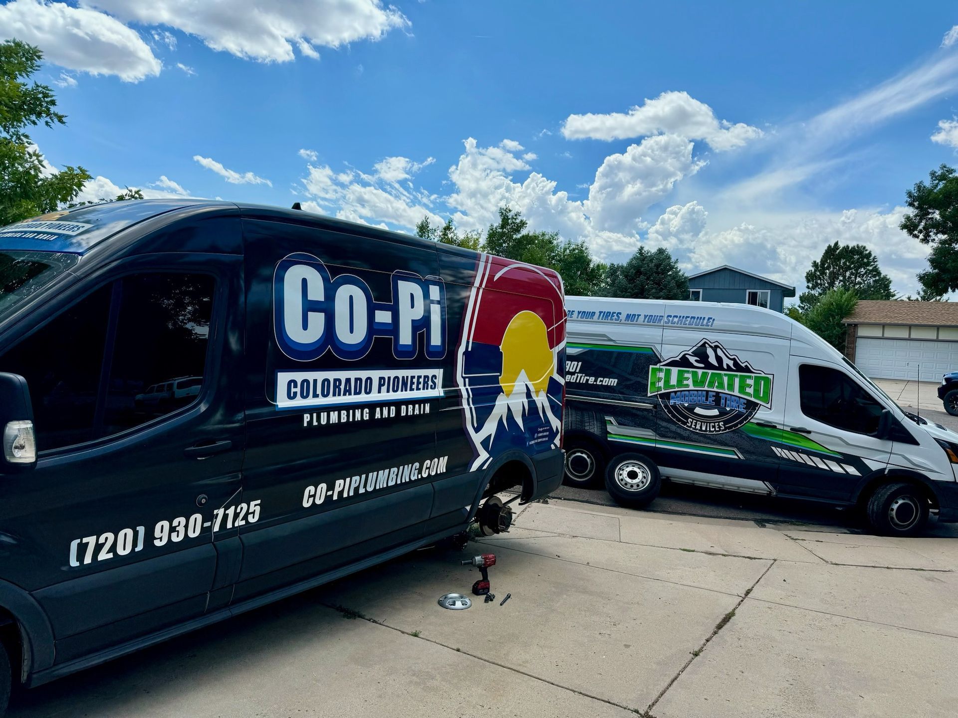 Two plumbing service vans with company logos parked outside on a sunny day.