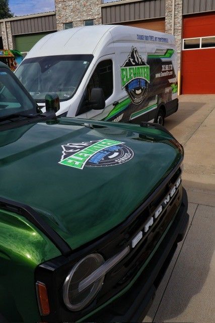 Green Bronco and white van with company logo.