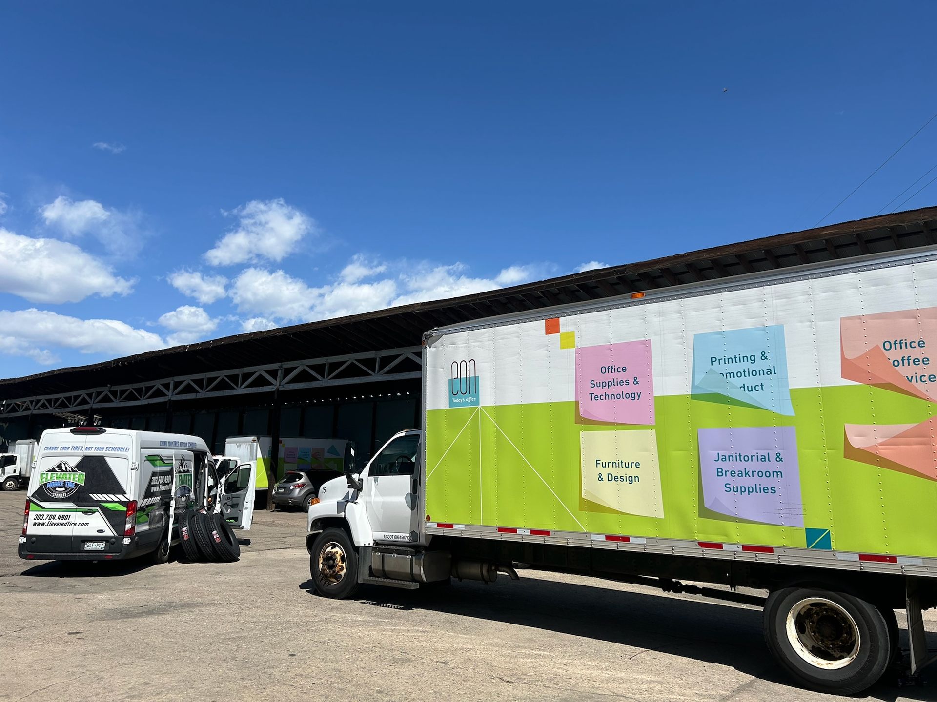 Truck with colorful sticky notes, parked outside a warehouse under a blue sky.