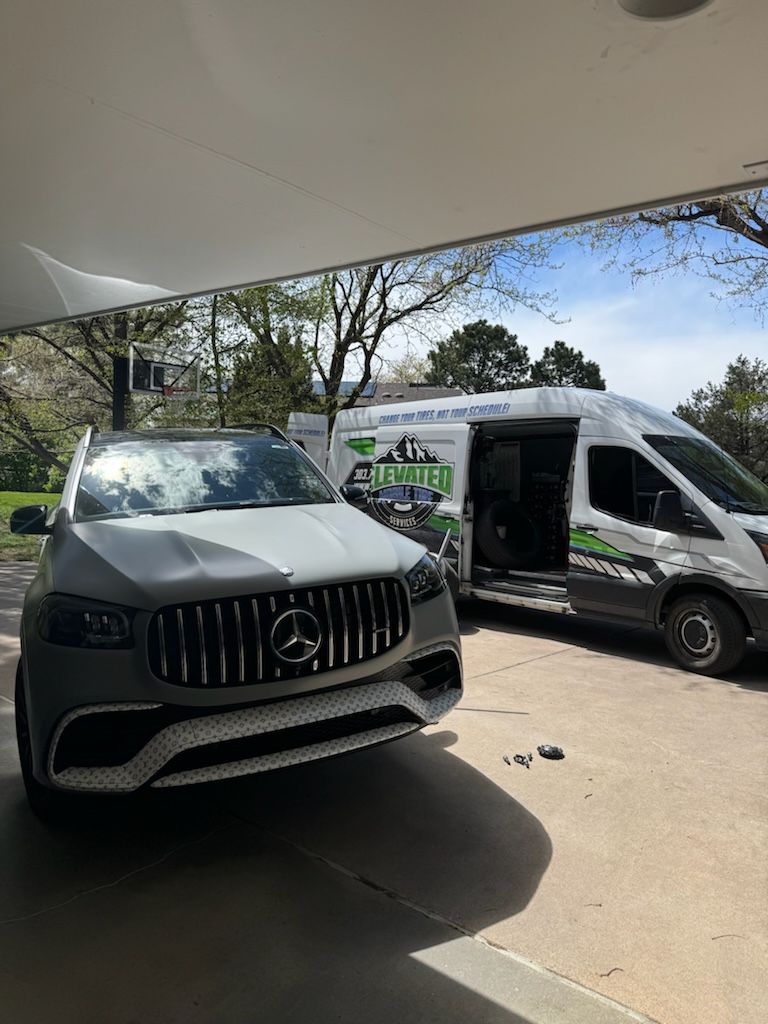 Gray Mercedes SUV parked next to a service van. Both are under a carport.