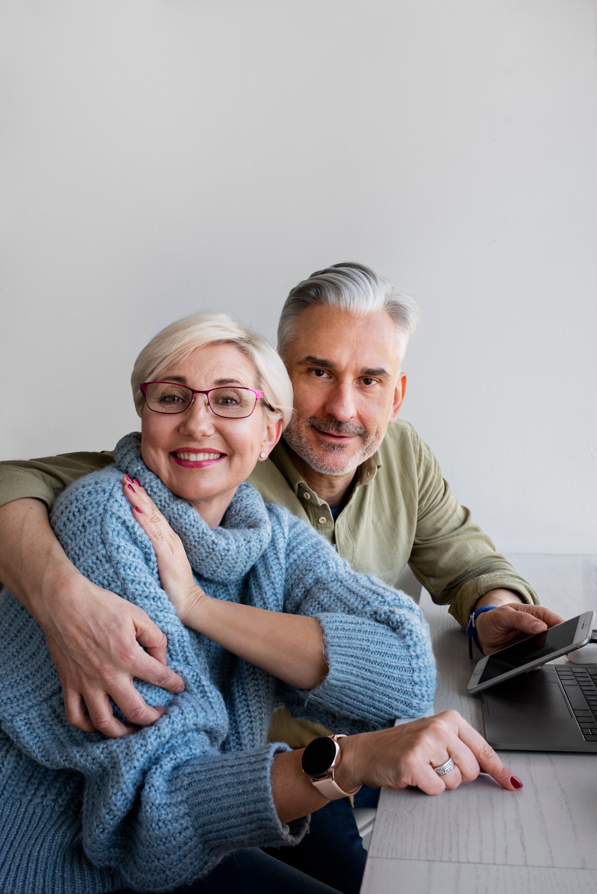 Senior couple smiling, looking at laptop. Man has arm around woman, pointing at screen.