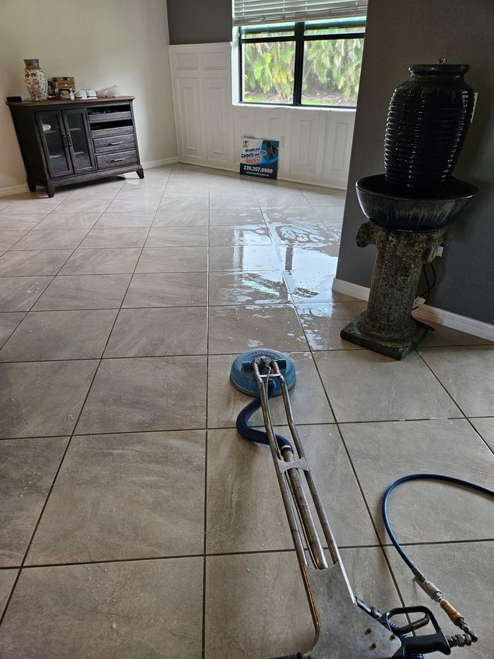 Living room with wet tiled floor and a carpet cleaner machine in the foreground