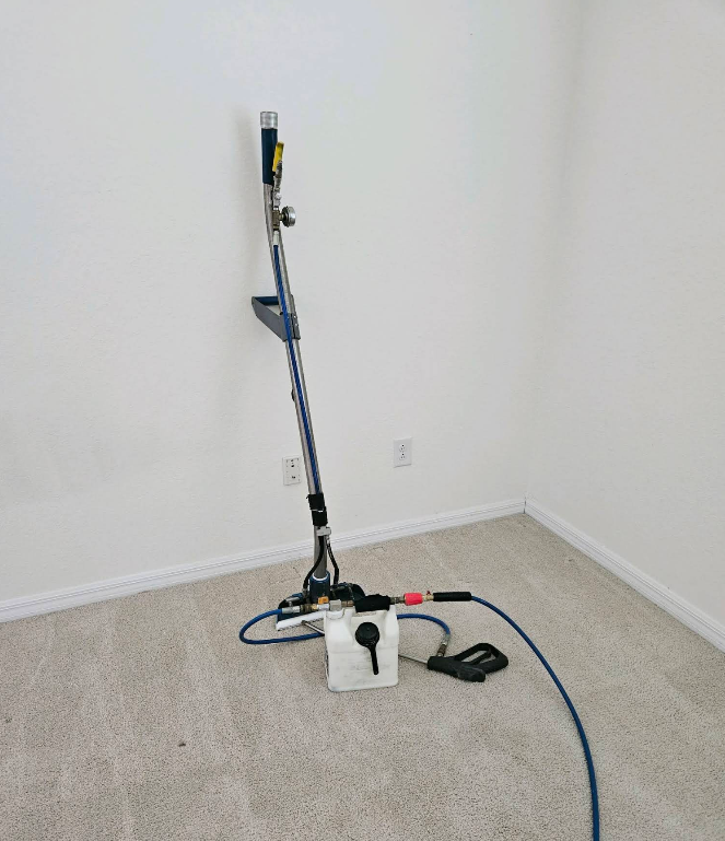 Floor-cleaning machine with blue hose and power cord in an empty corner room