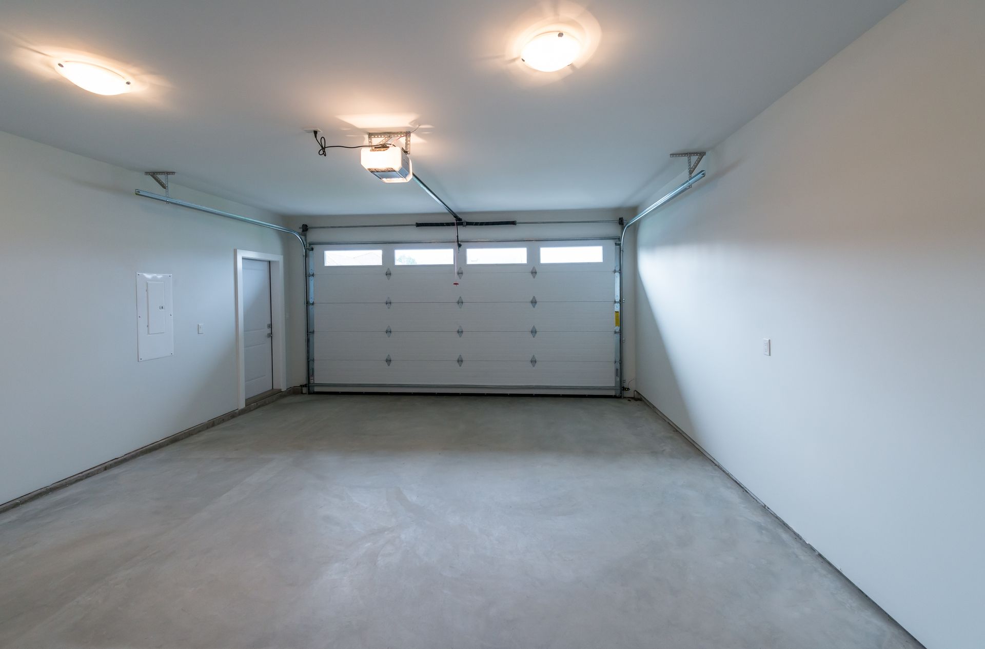 Empty garage interior with closed white garage door and concrete floor.