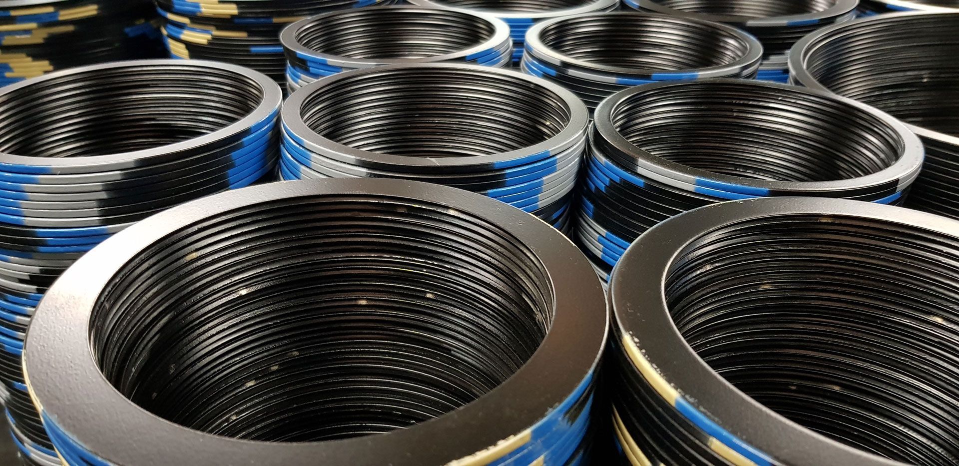 Close-up of numerous, stacked, circular metal gaskets, some with blue bands.