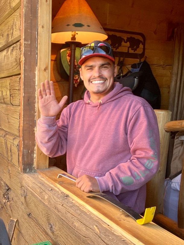 A man in a pink hoodie is waving from a window