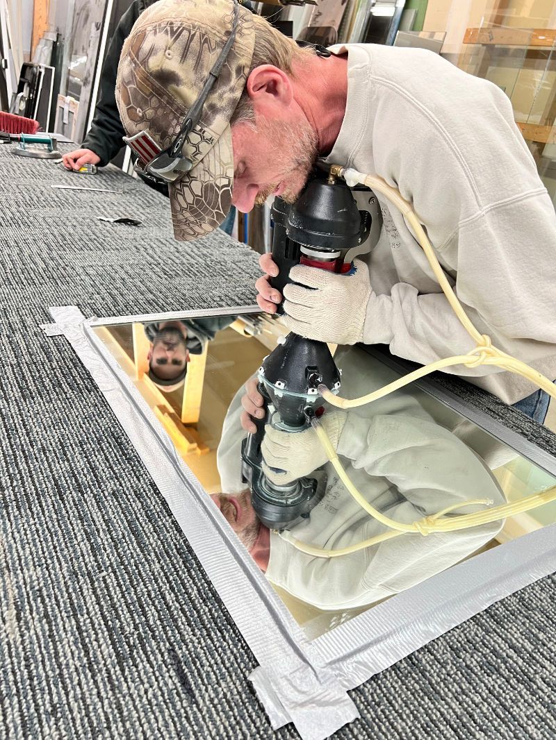 A man is working on a mirror with a drill.