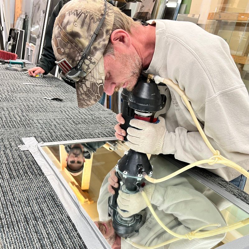 A man in a camo hat is working on a mirror