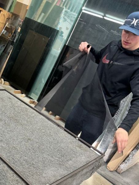 A man wearing a nike hat is holding a large piece of glass.