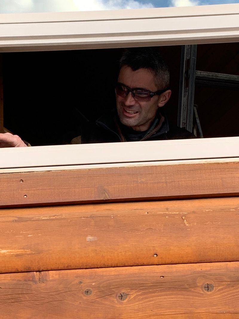 A man wearing glasses is looking out of a window