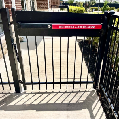 Black metal gate with a red sign that reads, 