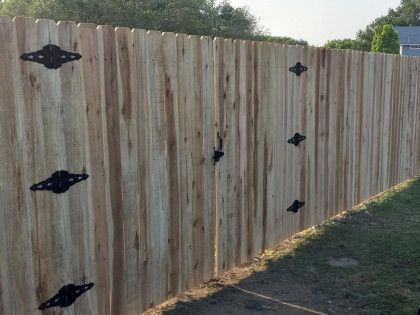 Wooden fence with decorative black hardware, in a grassy setting.