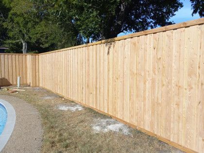 Wooden fence bordering a pool, surrounding dry grass.
