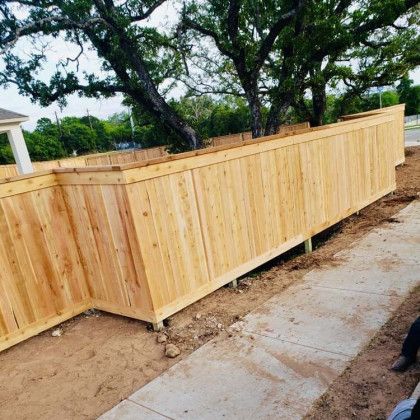 Wooden fence along a sidewalk, built around a tree.