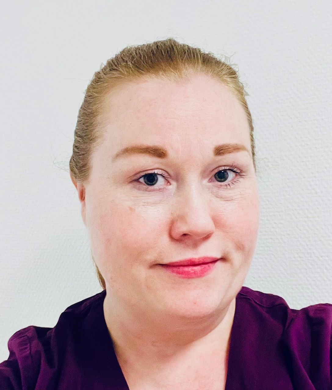 Tannlege Christian med briller og skjegg, iført blå skjorte og medisinsk maske, smiler til kameraet.