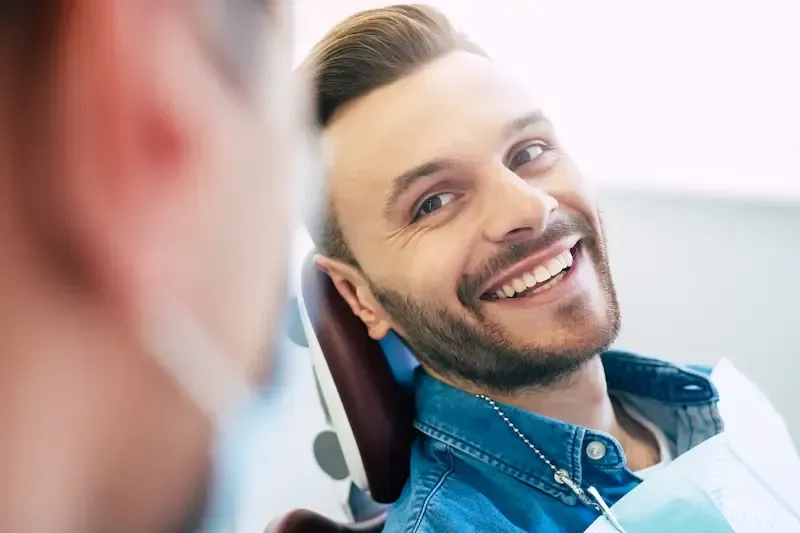 Kvinne som smiler, med vind i håret, utendørs, iført rosa jakke, naturskjønn bakgrunn.