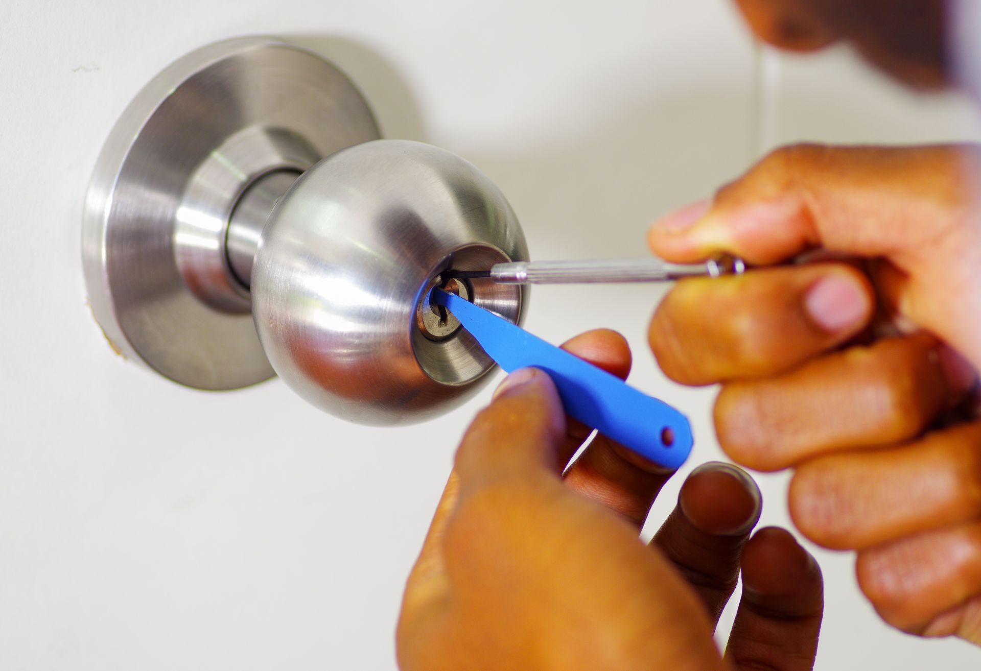 Close-up of a locksmith's hand picking a lock with a pick tools