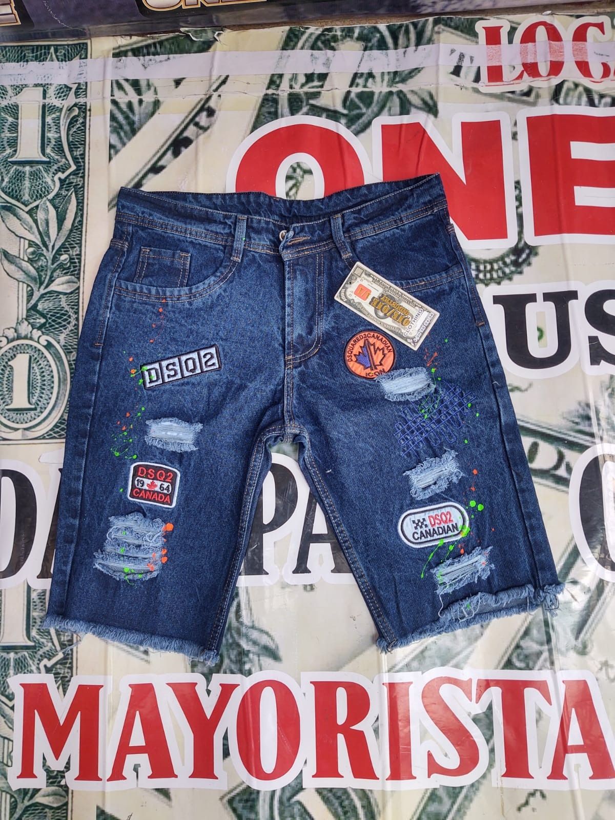 Un par de pantalones cortos de mezclilla encima de un billete de dólar.