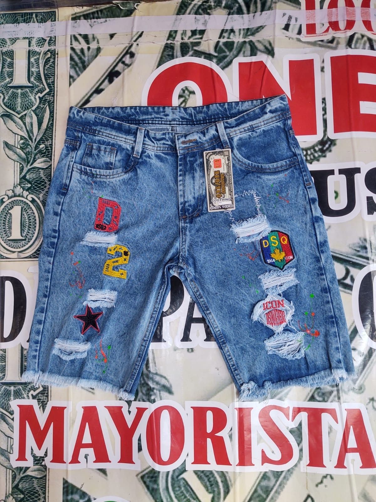 Un par de pantalones cortos de mezclilla encima de un billete de dólar.