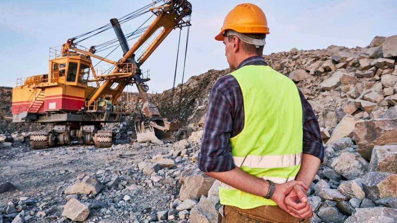 Worker in safety gear standing in front of construction area.