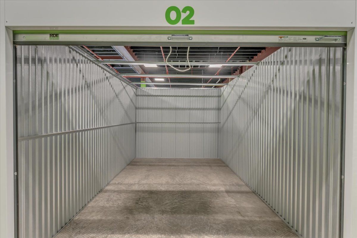 Interior of an empty, metal storage unit with an open overhead door, the number 