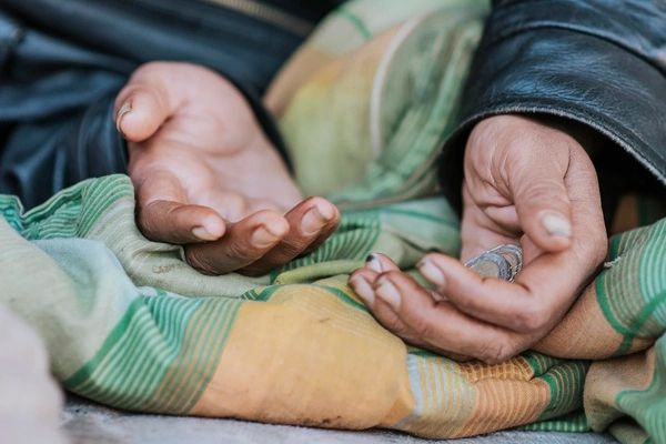 Open hands of a person, resting on a blanket, with dark jacket visible.