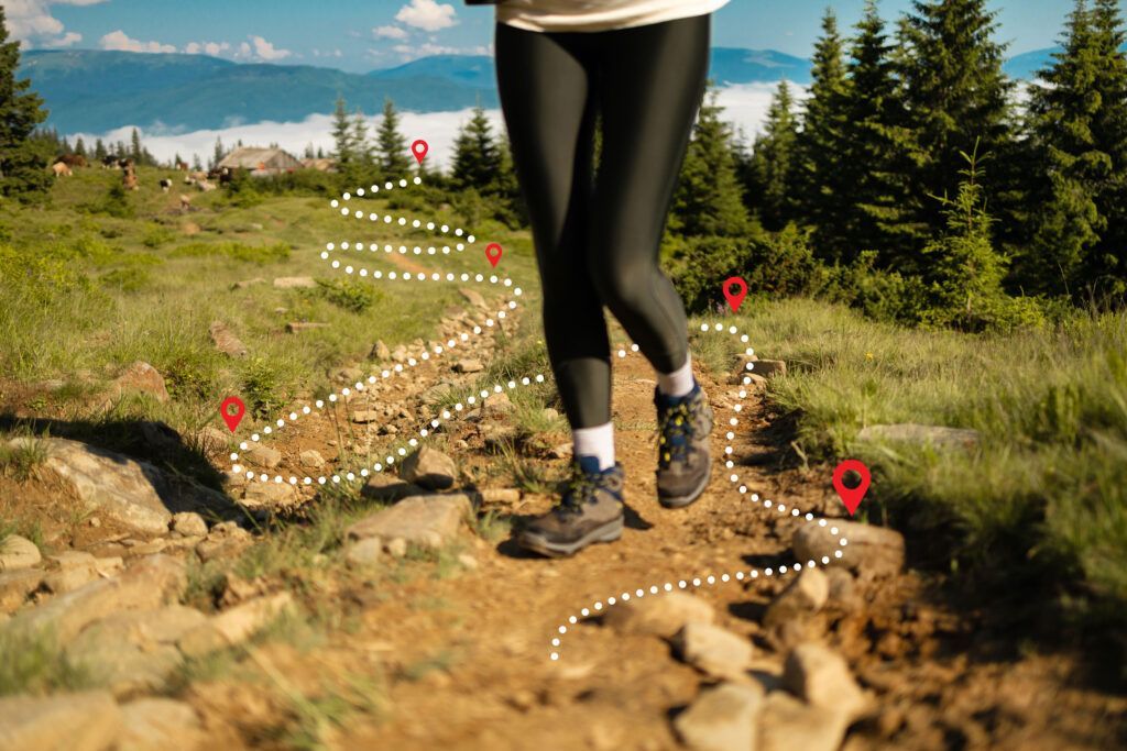 Person hiking on a trail in a mountain landscape, marked by a dotted line with location pins.