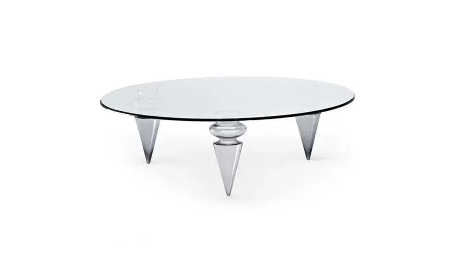 Tavolino ovale in vetro con tre gambe appuntite su sfondo bianco.