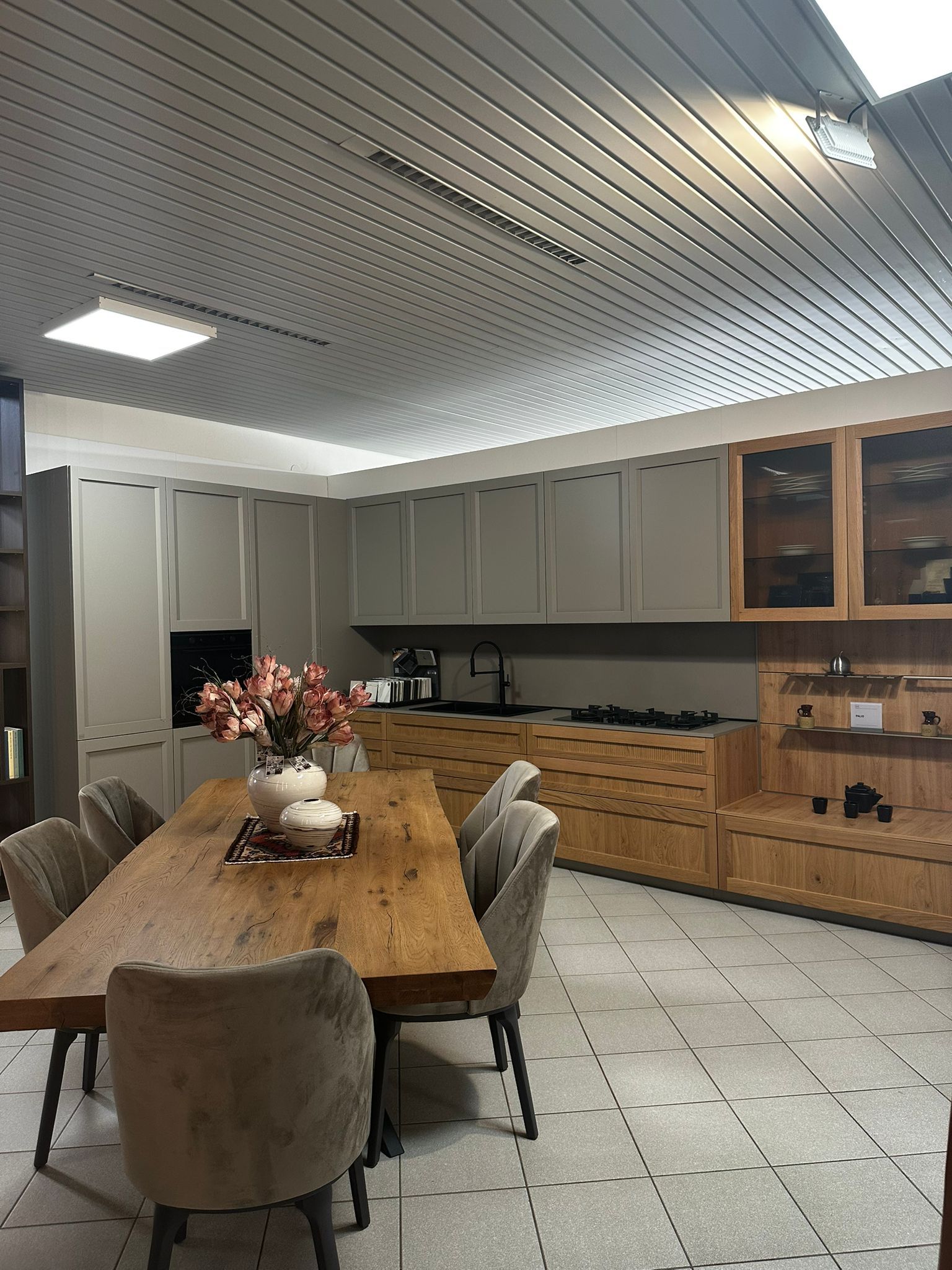 Una sala da pranzo con tavolo e sedie in legno e una cucina dai colori chiari.