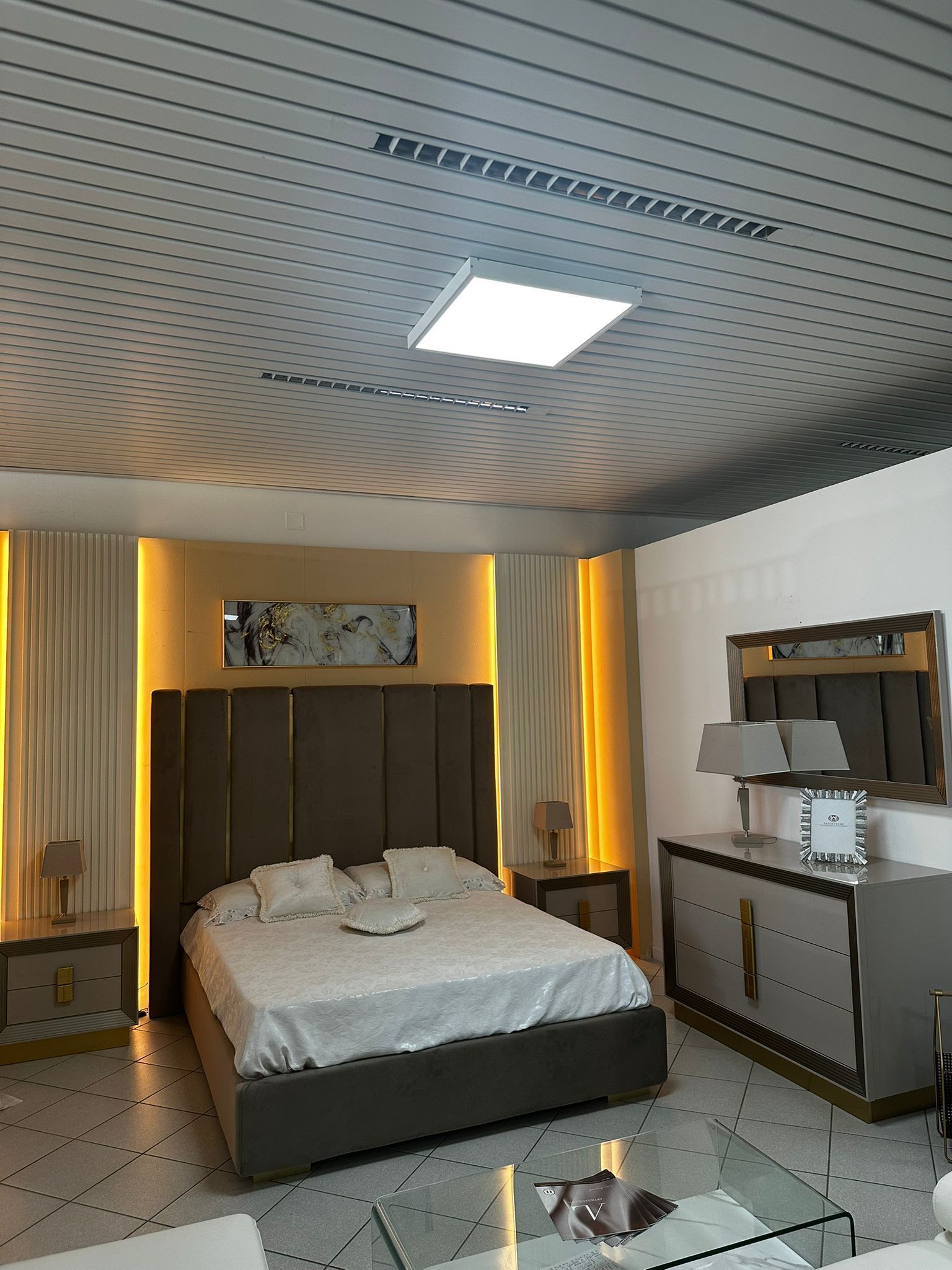 Camera da letto con letto, comodini, cassettiera e soffitto con illuminazione da incasso.