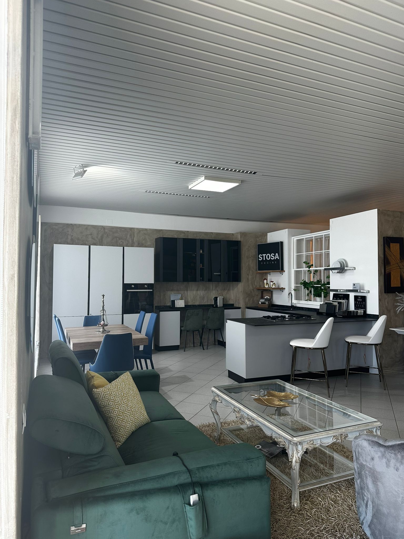 Una cucina e un soggiorno open space con divano verde, isola e tavolo da pranzo.