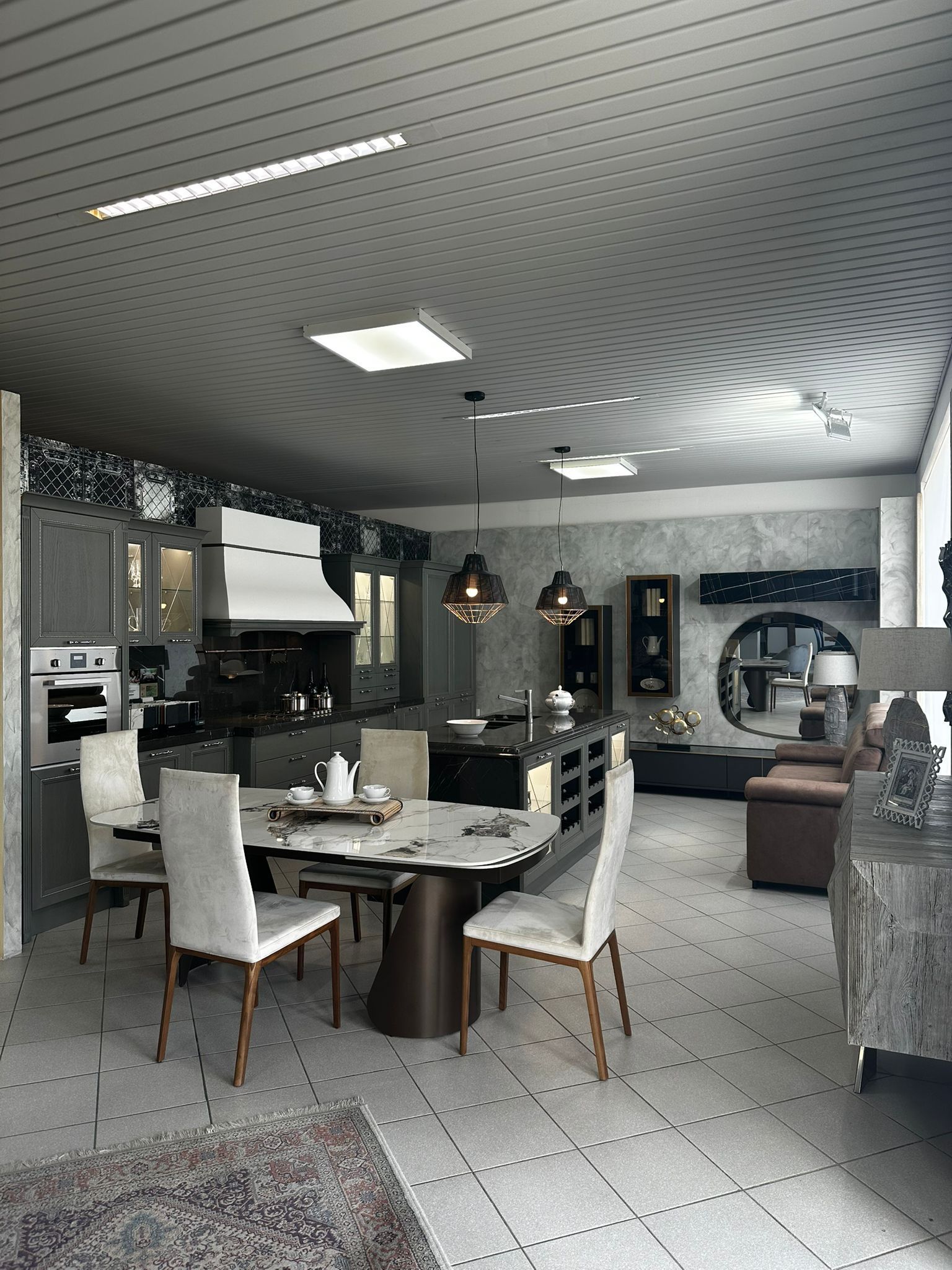 Cucina e sala da pranzo open space con mobili moderni. Colori neutri, soffitto decorato e isola scura.