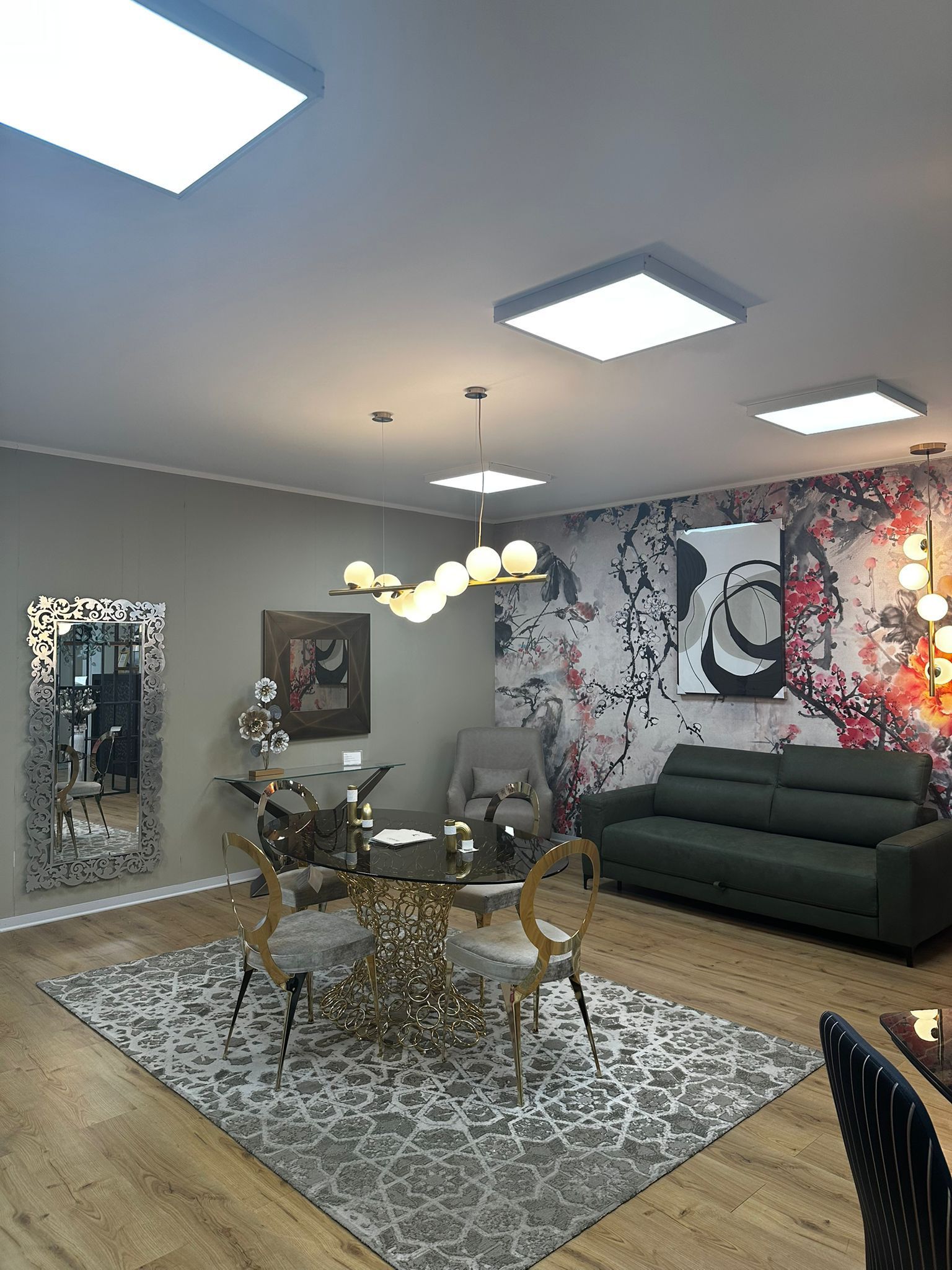 Una moderna sala da pranzo con un tavolo dorato, sedie, un divano verde e un tappeto a fantasia.