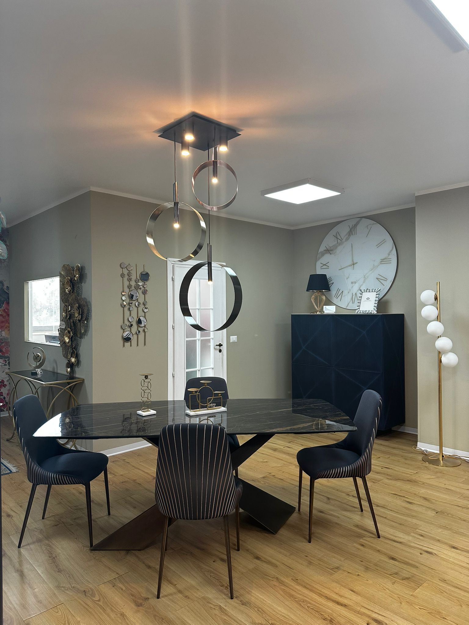 Sala da pranzo con tavolo nero, sedie, lampadario, decorazioni in marmo e pavimenti in legno.