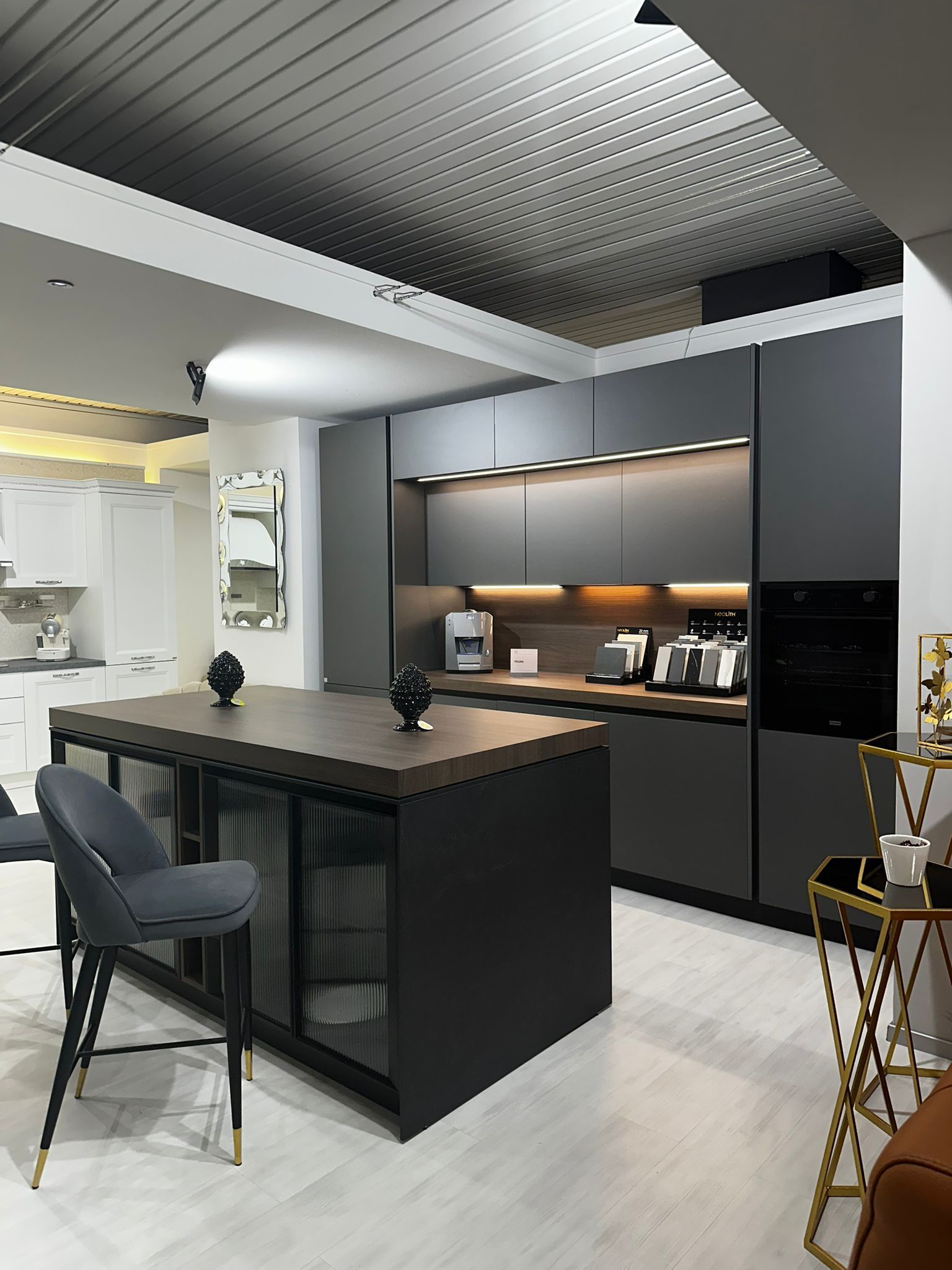 Cucina moderna con mobili grigio scuro, isola con sgabello da bar ed elettrodomestici da incasso.