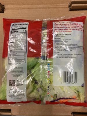 A bag of lettuce is sitting on top of a cardboard box.